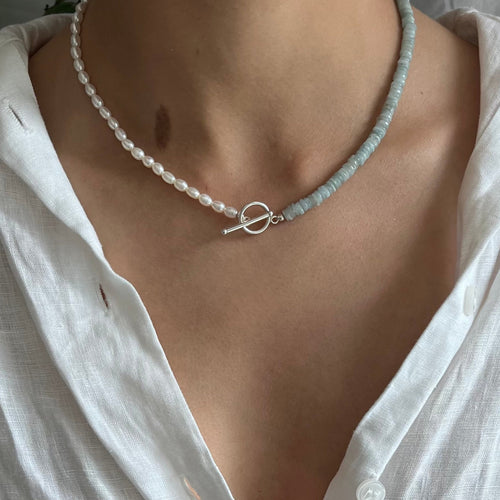 Pearl necklace worn by a person in a white shirt with a neutral background