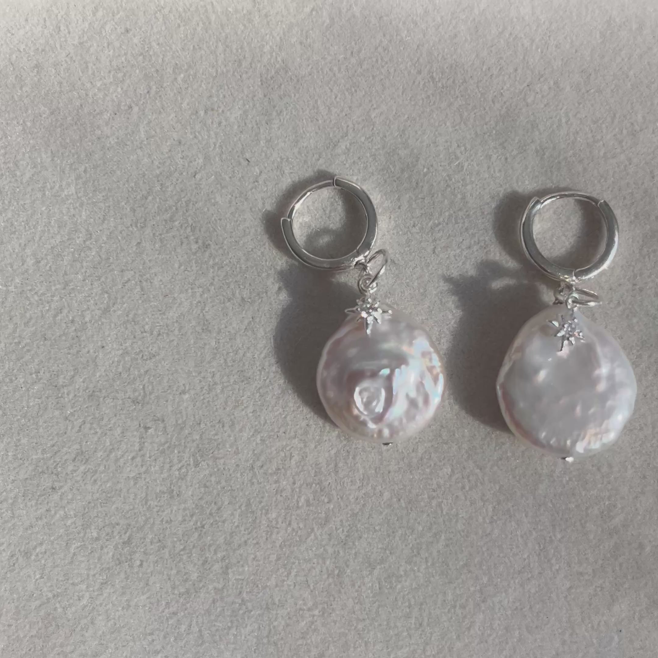 Pair of pearl earrings on a grey background